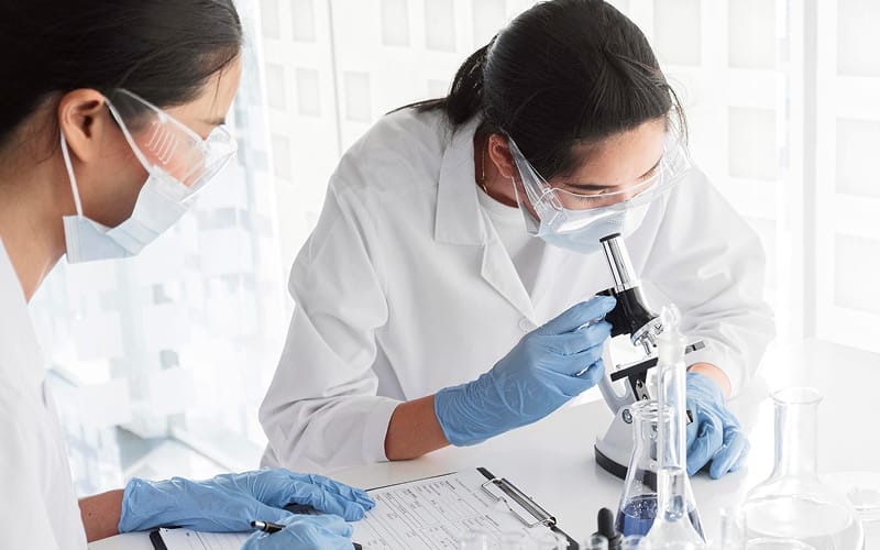 Researchers using a microscope in a life science lab.