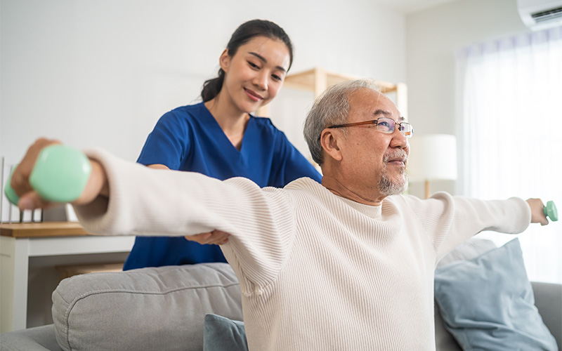allied health professional helping an elderly patient with workout