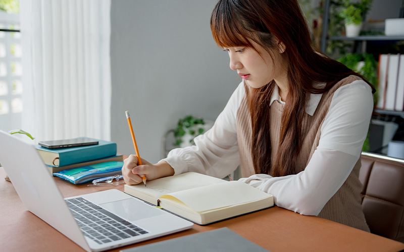Woman taking notes on a laptop.