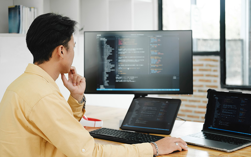man in a yellow shirt focused on coding
