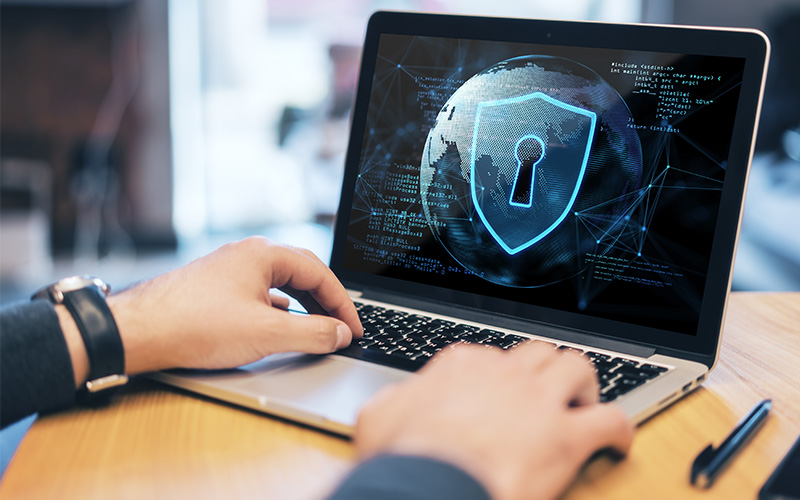 Person typing on laptop with cybersecurity icon overlay