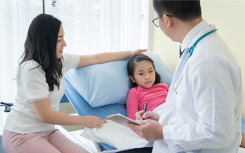 doctor looking at a child patient accompanied by a parent