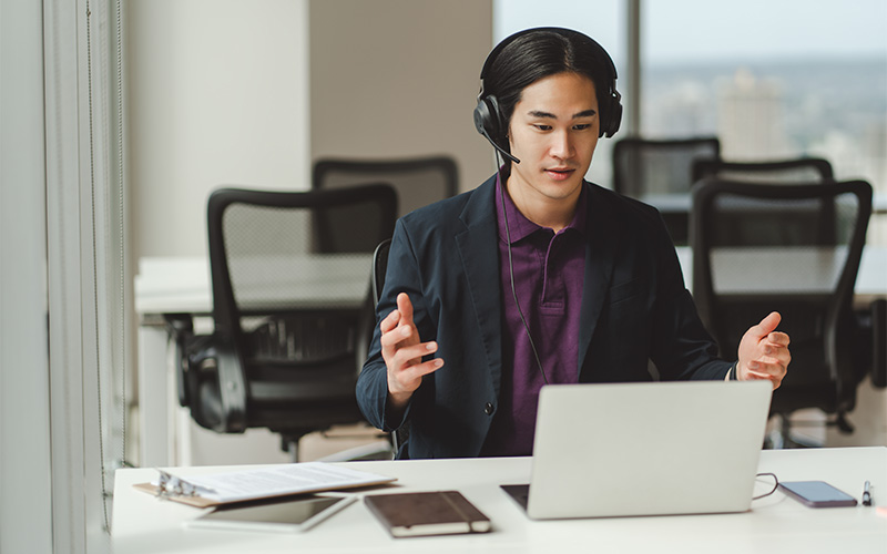 person with headphones sits at a desk in an office