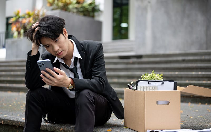 Man sitting on stairs, looking stressed after retrenchment.