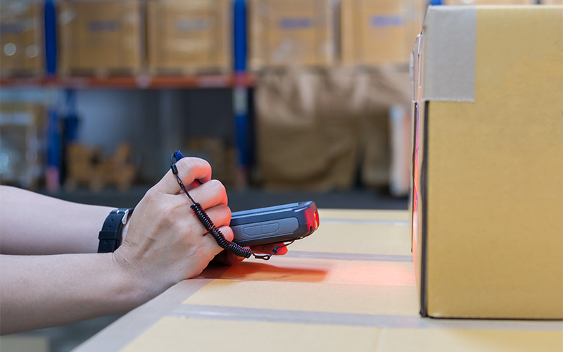 Close-up of worker scanning a cardboard box in a warehouse