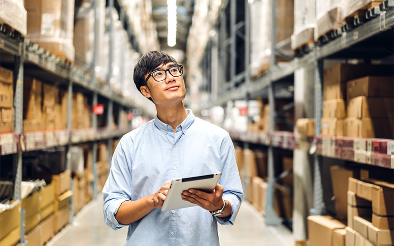 Man inspecting warehouse inventory using a tablet