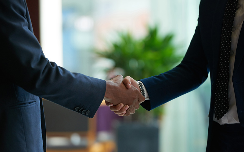 Two professionals shaking hands, adapting to AI.